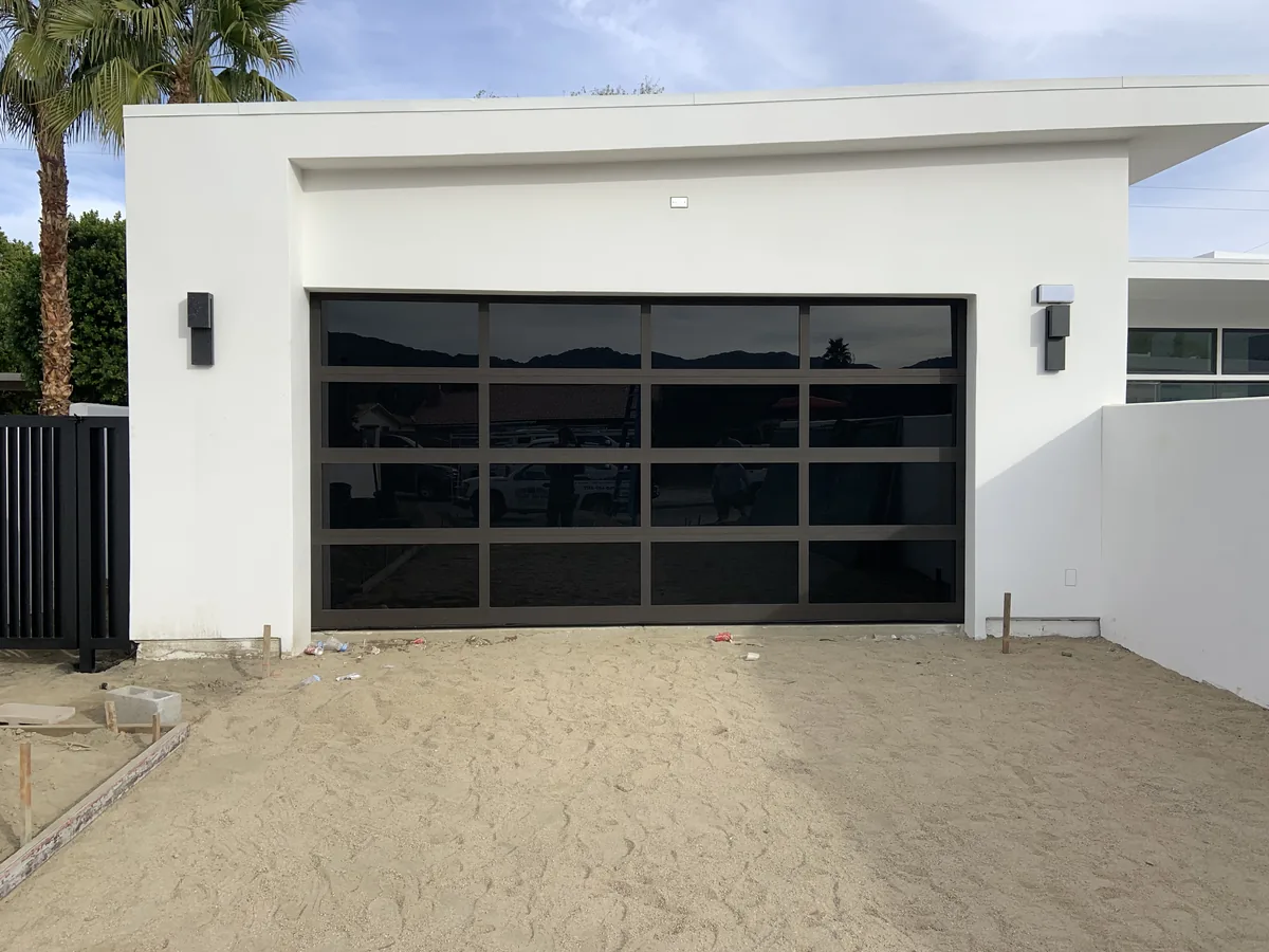 Black framed full view glass garage door on a white stucco home