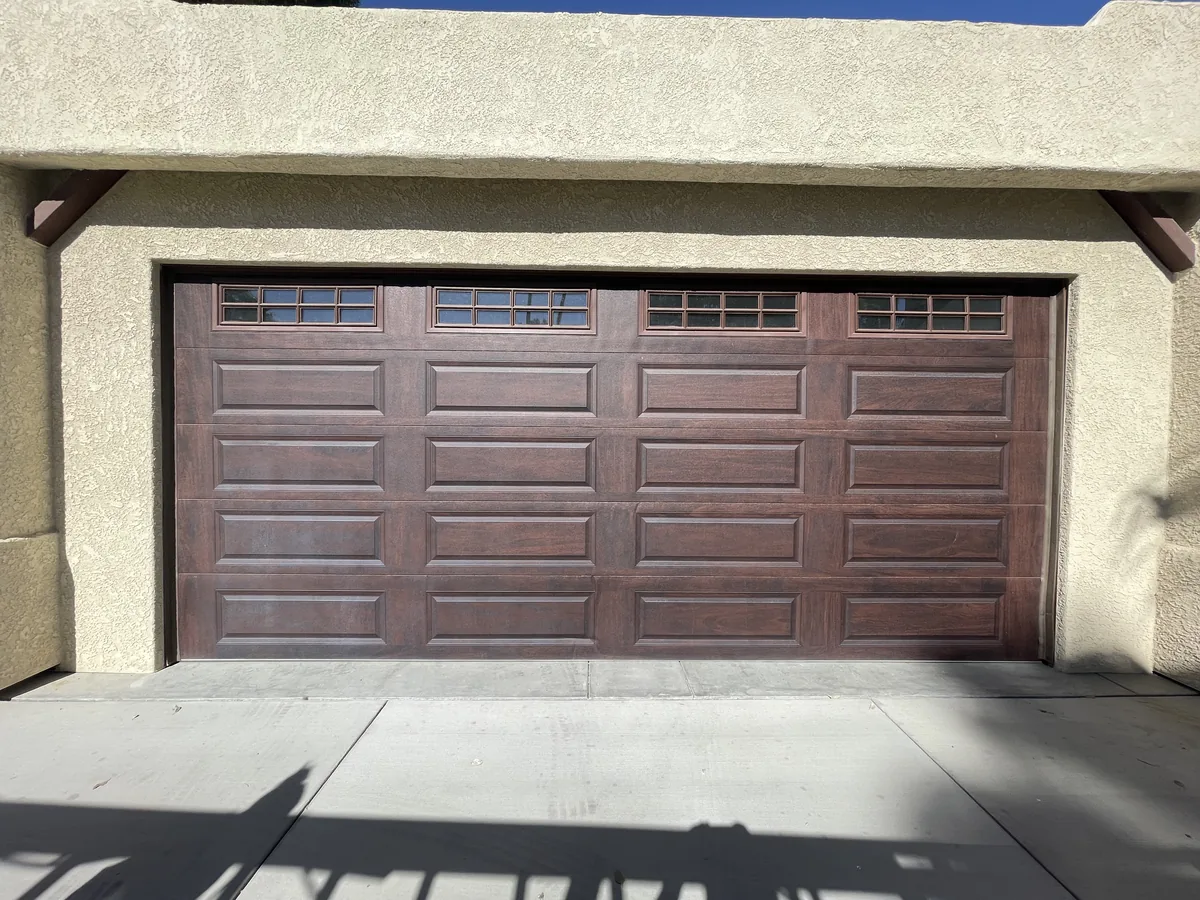 Brown carriage style garage door with a row of square windows