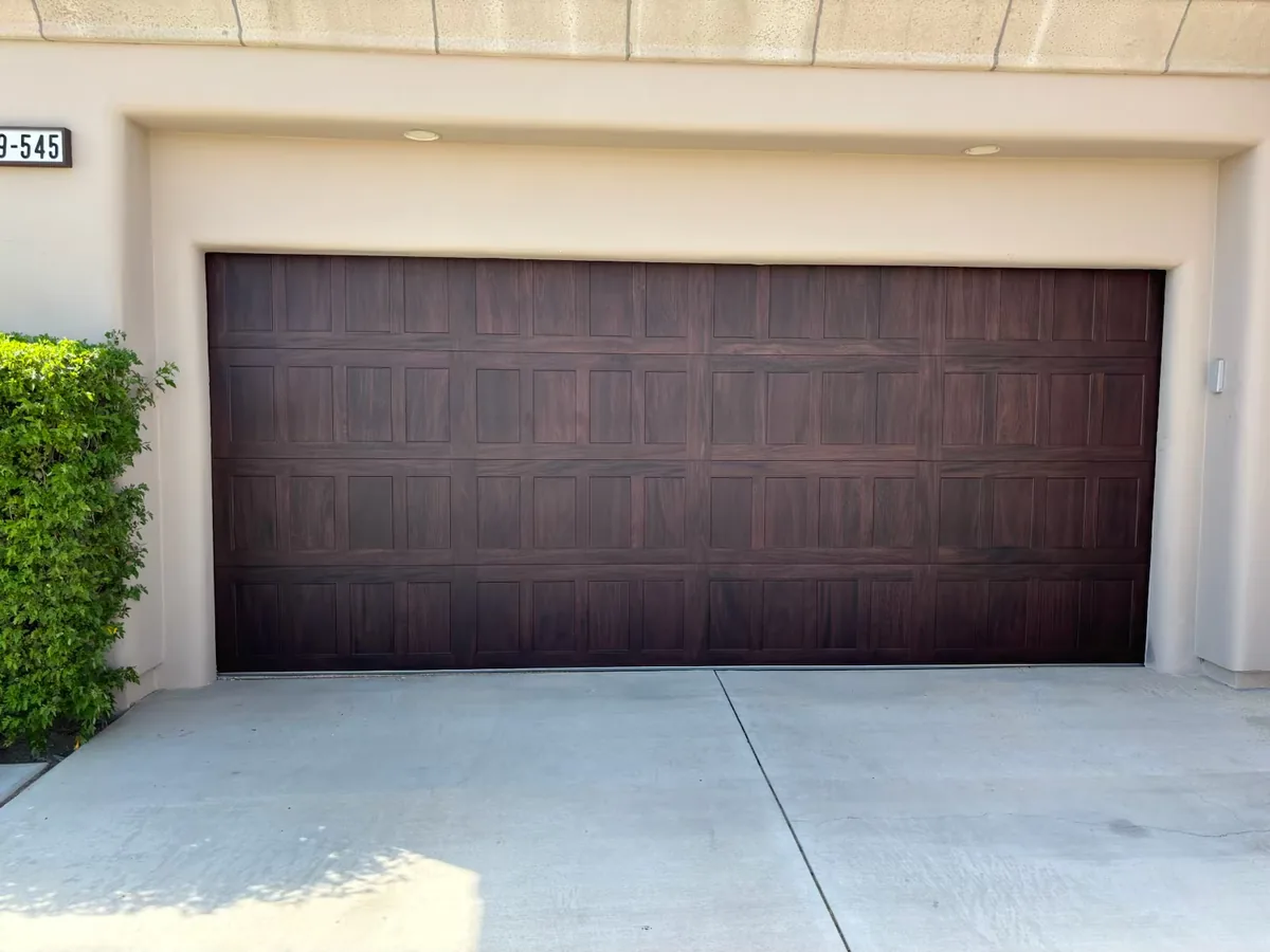 Dark brown raised panel garage door on a stucco home