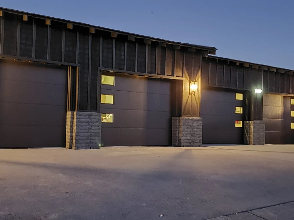 Dark garage doors with lit window inserts on a multi bay garage