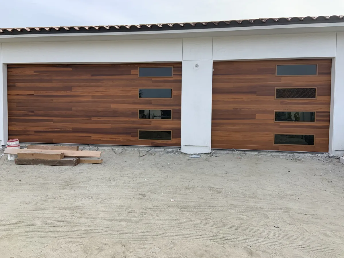 Walnut tone modern garage doors with window slots on a double and single bay