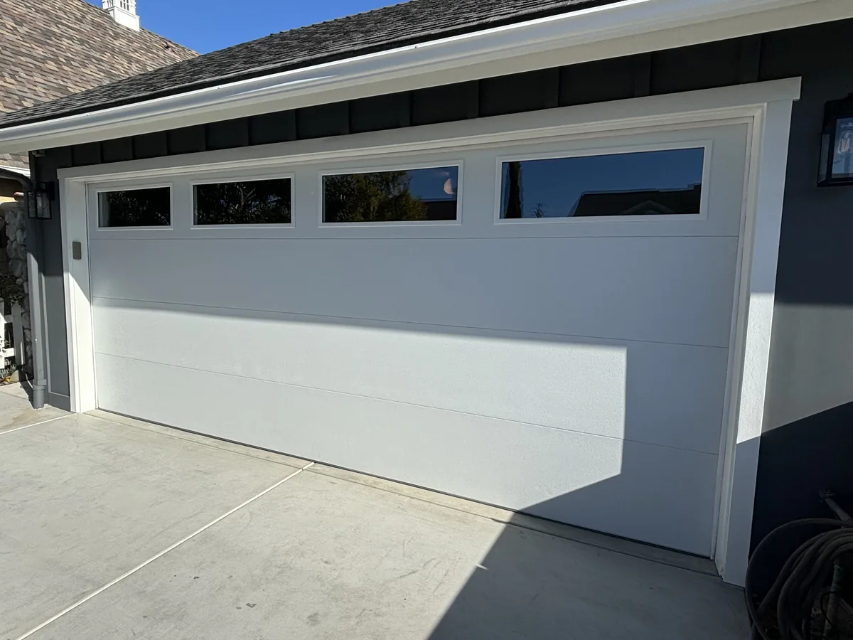 White garage door with a row of windows across the top panel