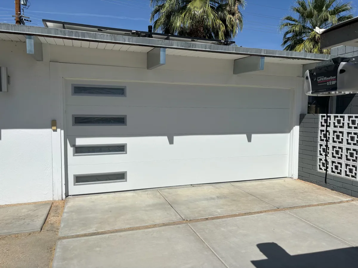 White modern garage door with vertical window slots and a matching gate